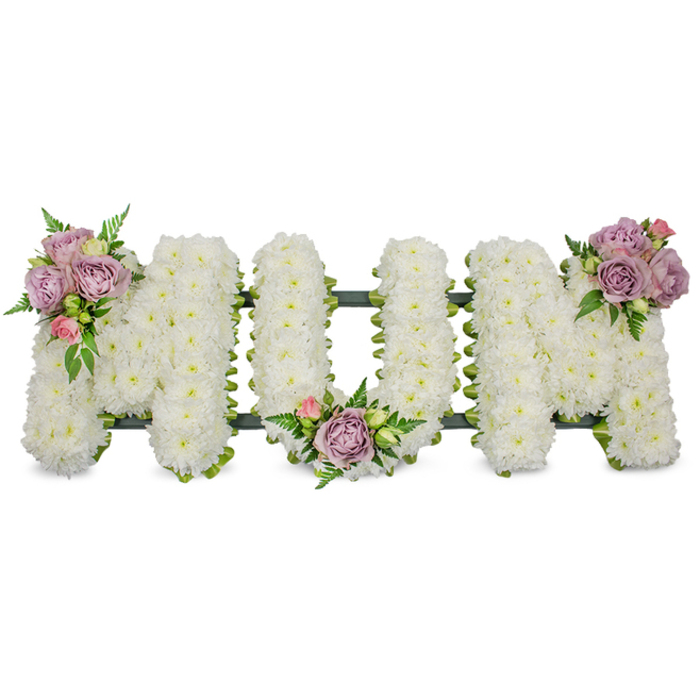 A heartfelt and meticulously assembled floral tribute spells the word 'MUM' in three generous, upright letters, each entirely covered in a dense carpet of small, fresh white chrysanthemums that produce a plush, velvety texture across the surface. The white blooms read as luminous and serene against a pure white photographic backdrop, evoking a sense of peace and respectful remembrance. To introduce gentle colour and a human touch, three artful clusters of accent flowers are positioned with intent: the first nestles on the upper left arm of the opening 'M', composed of soft lilac roses, a few pale pink rosebuds and bright green foliage; the second settles gracefully in the centre curve of the 'U', repeating the palette of muted lavender and blush; the third mirrors the first on the upper right curve of the closing 'M', creating symmetry and a measured rhythm across the design. Slim fern fronds and lighter green leaves weave through and around these clusters, adding texture, depth and movement that catches the soft studio light. A dark green structural base-either a ribbon-wrapped frame or moss-covered foam-runs along the base of the letters and subtly outlines the shape beneath the white flowers, giving the tribute a solid, three-dimensional presence suitable for standing at a funeral service or graveside. As a local florist working near Wapping and the historic docks, Flowers Wapping crafts this sort of bespoke memorial with careful attention to proportion, sentiment and the quiet dignity families seek during a service. The overall impression is one of thoughtful restraint: pure whites for solace, pastel roses for affectionate memory, and green accents to connect the tribute to life and place.