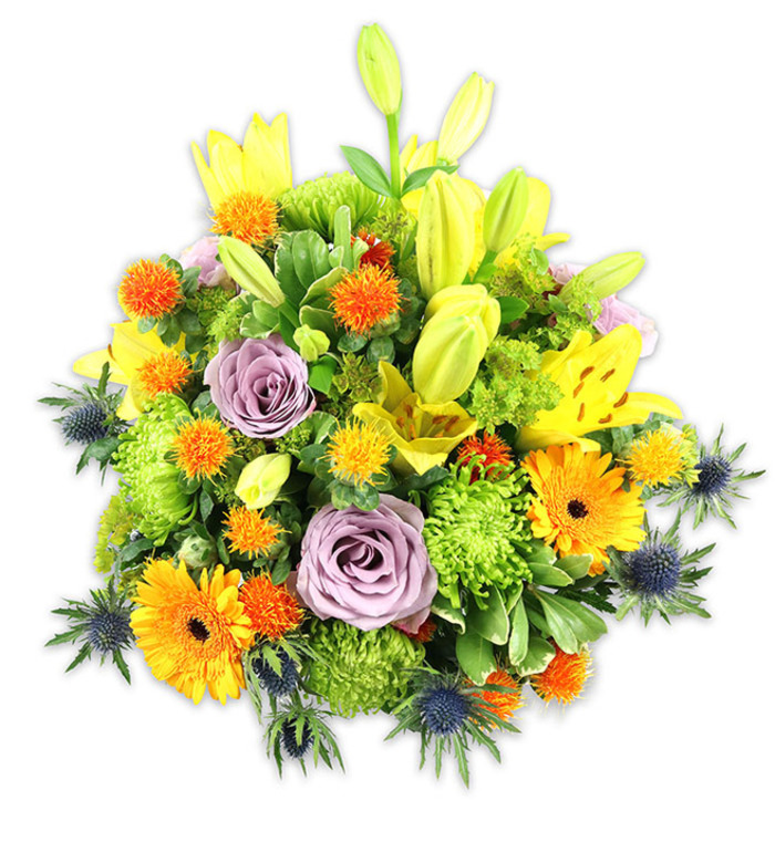 A carefully crafted, vibrant centerpiece shown on a stark white background so each hue and texture reads clearly, evoking the lively spirit of the Wapping riverside. Several bright yellow Asiatic lilies dominate the silhouette, some fully unfurled to reveal freckled throats and stamens, others elegantly elongated as buds that add vertical emphasis and a feeling of promise. Cheery orange Gerbera daisies pepper the composition with broad, sunlit faces, their flat petals fanning out around darker centres to create focal points of warmth. Two or three soft lavender-purple roses are tucked near the centre, their petals curling inward in a soothing spiral and lending an air of classic refinement. Ample lime-green cushion chrysanthemums create a plush, textured base that makes the arrangement read as generous and abundant; small spherical, spiky orange and yellow accents contribute vivacious pops of colour and a playful, festival-like texture. Blue-grey Eryngium thistles rise along the lower and side edges, their sculptural, star-shaped bracts introducing a cool, slightly maritime note-a nod to the nearby Thames and historic docks. Mixed leafy greens, from broad lily foliage to smaller glossy fillers, weave through the blooms to add depth, shadow and a fresh-cut scent. The overall effect is celebratory yet composed, suited to anniversaries, housewarmings, or expressions of sympathy delivered with care. As if prepared for a table at a weekend market near The Highway or a quiet living room on Narrow Street, this bouquet combines traditional elegance with a modern, textural twist.