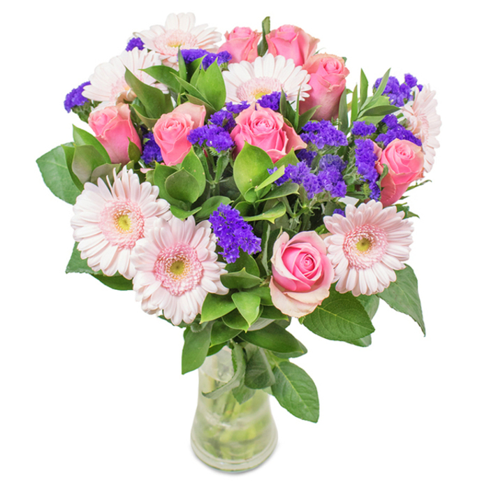 An artistically composed bouquet stands out in sharp relief against a pristine background, exuding both charm and sophistication that captures the essence of Wapping's riverside life. Approximately eight pink roses-some unfurling, others tightly wound-form the arrangement's soft centrepiece, their delicate spiral petals creating a sense of romantic promise. Interspersed among them, five or six pale pink gerbera daisies exhibit broad, sunlit faces edged in creamy ivory, reminiscent of blooms gathered from a springtime stroll near St. Katharine Docks. Clusters of vivid purple statice punctuate the design, adding striking visual contrast that mimics the lively hues of local weekend flower markets. Lush green foliage anchors the arrangement, suggesting a lively abundance and providing a foil for the brighter tones above. The transparent vase, filled with clear water and neatly trimmed stems, reflects both the freshness and intentional craftsmanship of a Wapping florist devoted to excellence. Perfect for marking a birthday, sharing affection with a loved one, or brightening an office by the river, this bouquet symbolises celebration and thoughtful sentiment rooted in Wapping's unique neighbourhood spirit.